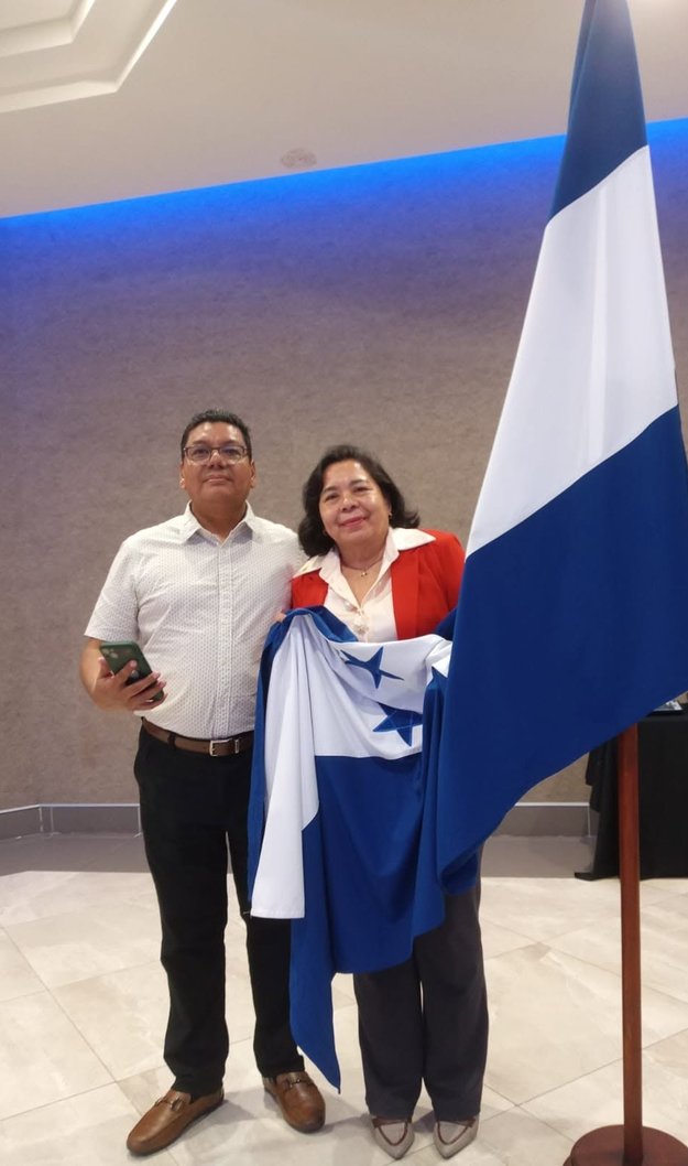 Juan Carlos Reyes, presidente del COHPUCP Zona Norte, junto a Norma Elizabeth López con la bandera de Honduras